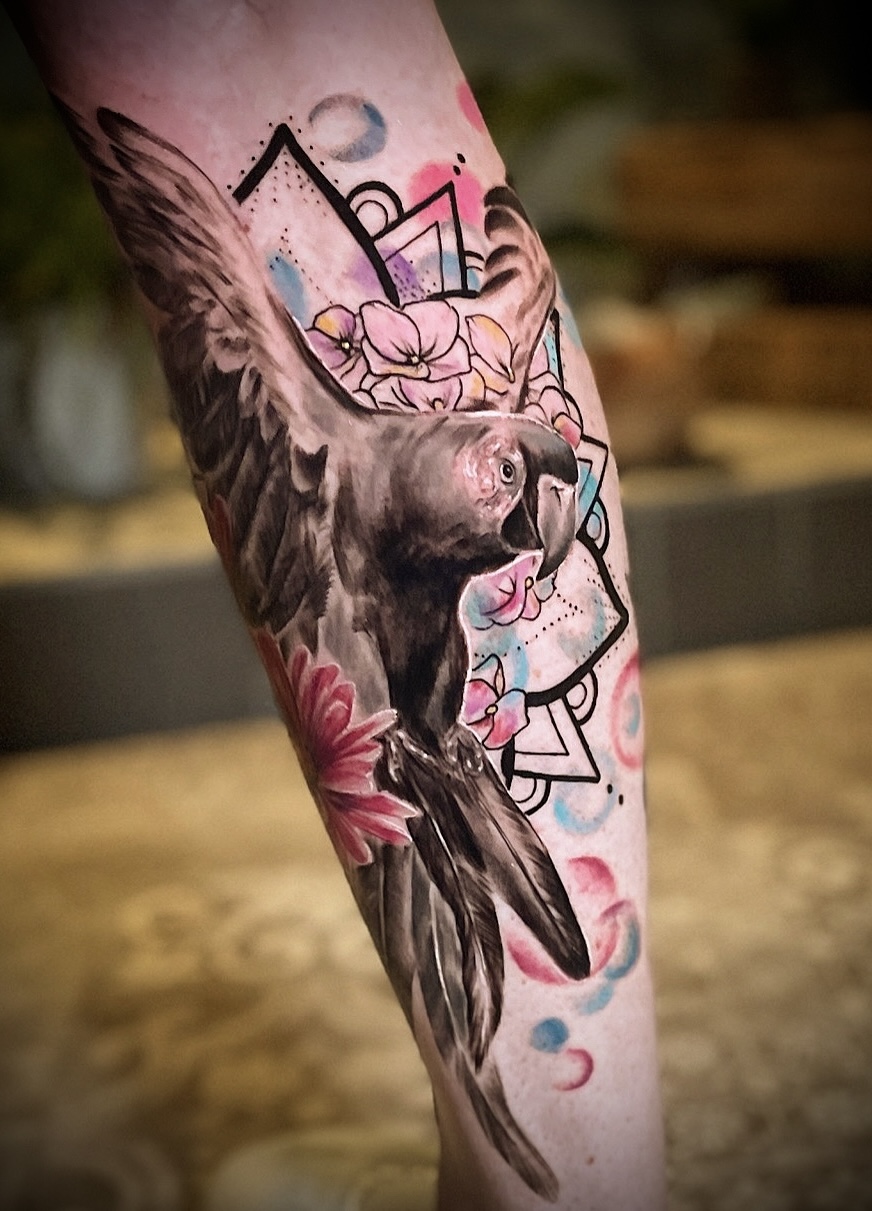 Papagei mit Blumen am Bein — buntes Tattoo von Pia Insel