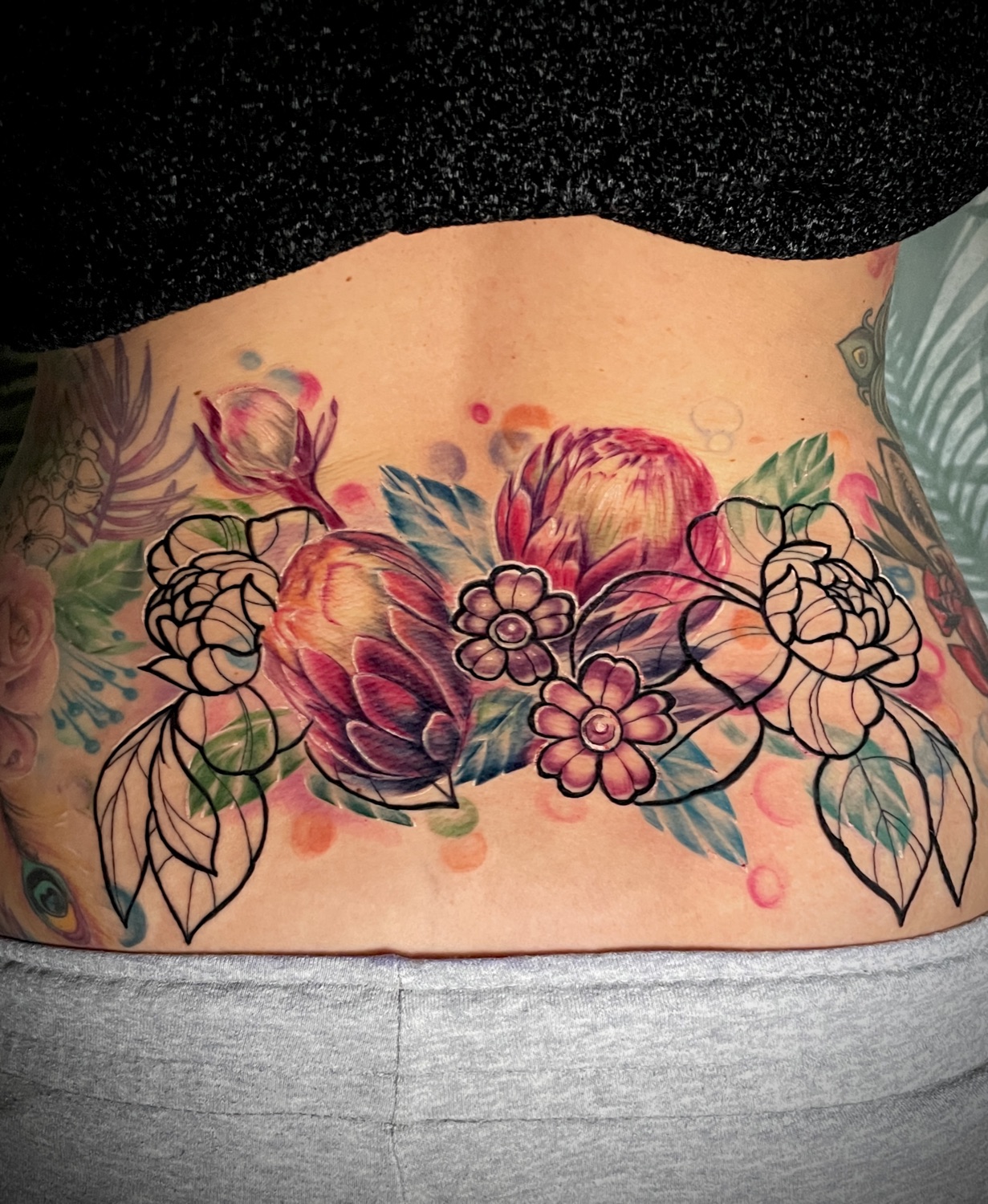 Blumen am unteren Rücken — buntes Tattoo von Pia Insel