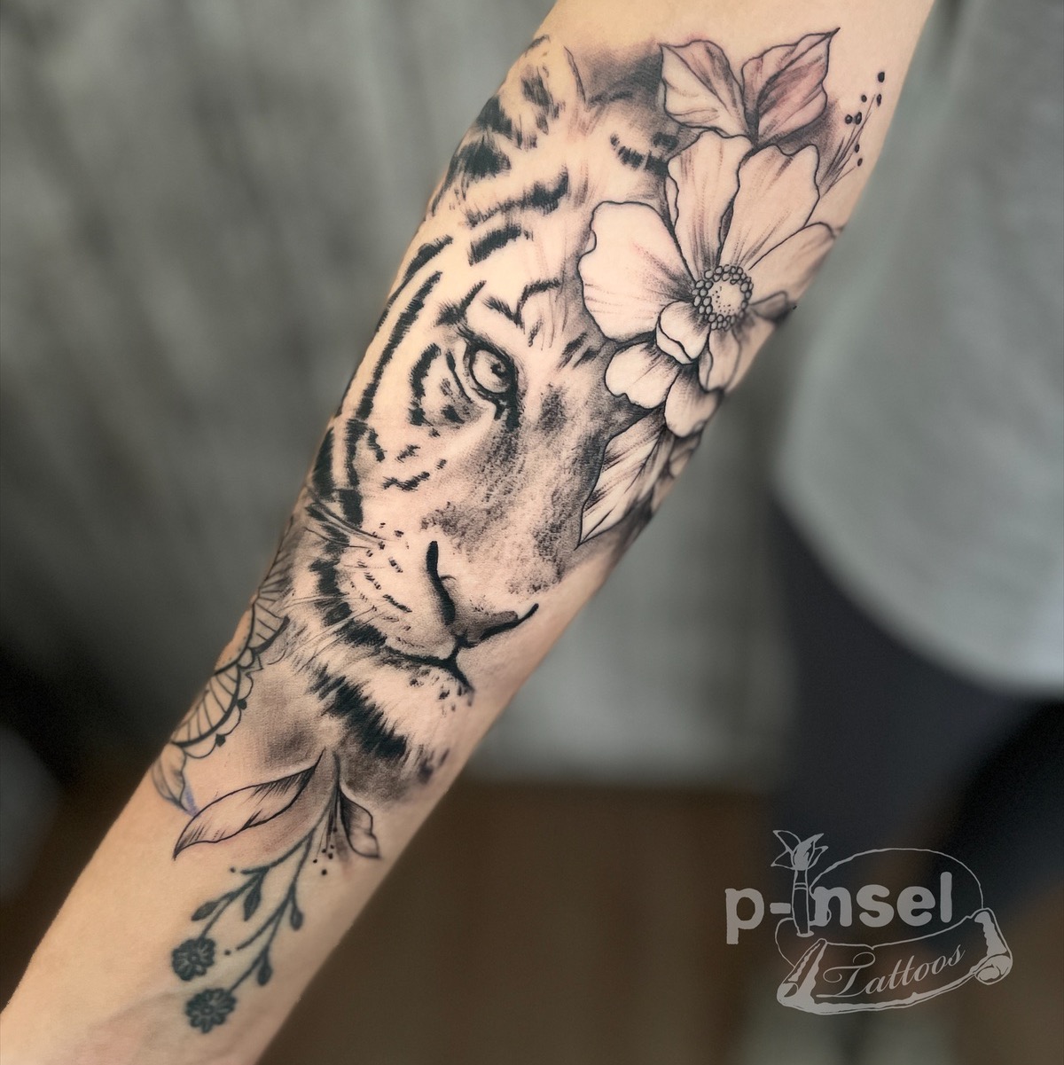 Tiger mit Blumen am Arm — schwarz-weiß Tattoo von Pia Insel
